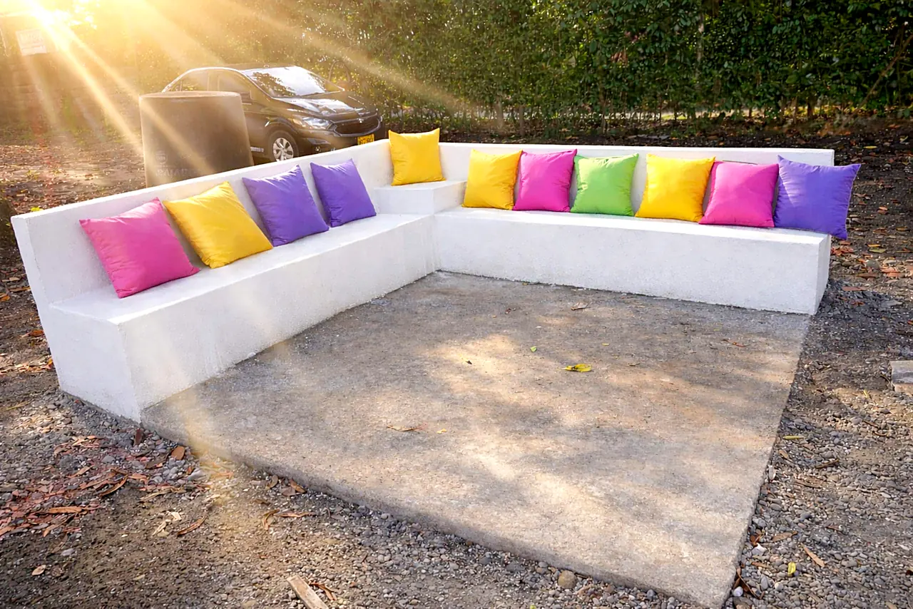 Zona de fogata al aire libre con banca y cojines de colores al atardecer